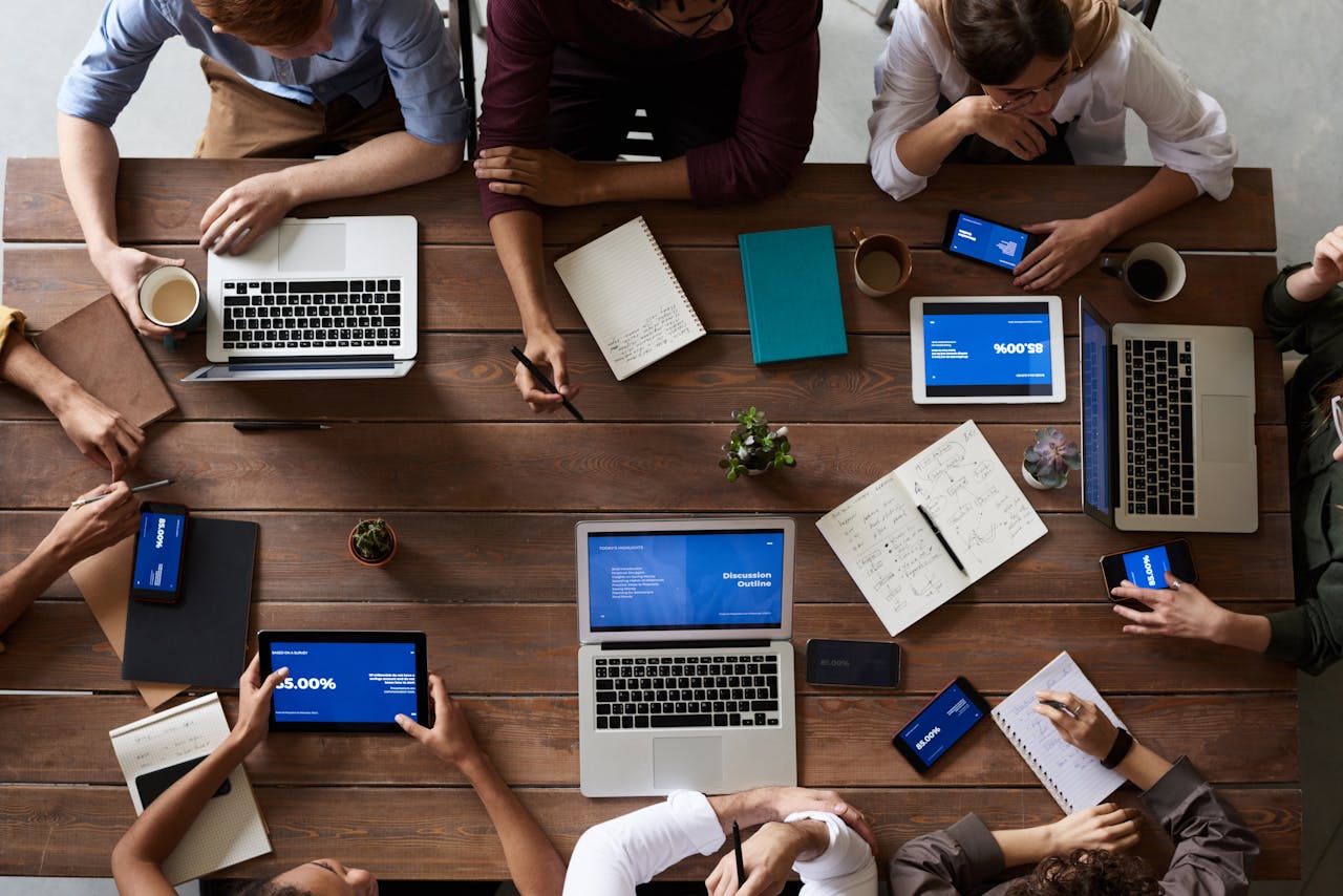 about-02 Overhead view of a diverse team in a business meeting using laptops and tablets.