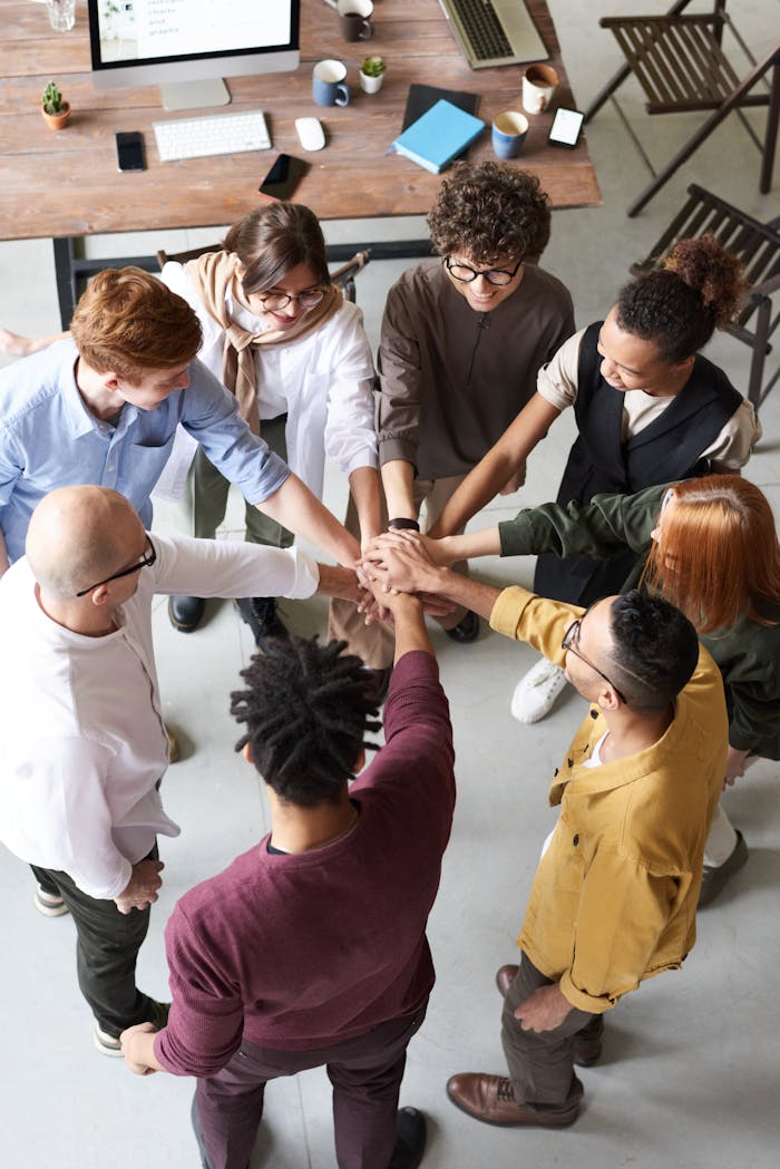 Mastering the First Impression: Your intriguing post title goes here A diverse group of professionals joins hands in a team-building exercise indoors.