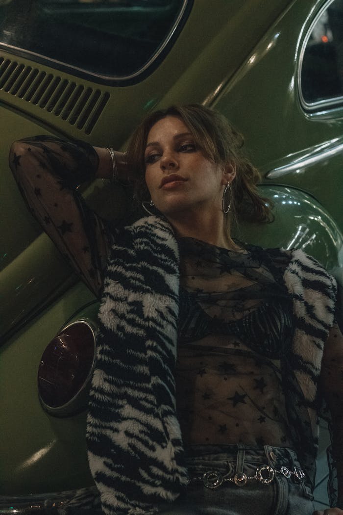 our-services-3 Fashionable woman posing by a green vintage car in moody lighting.