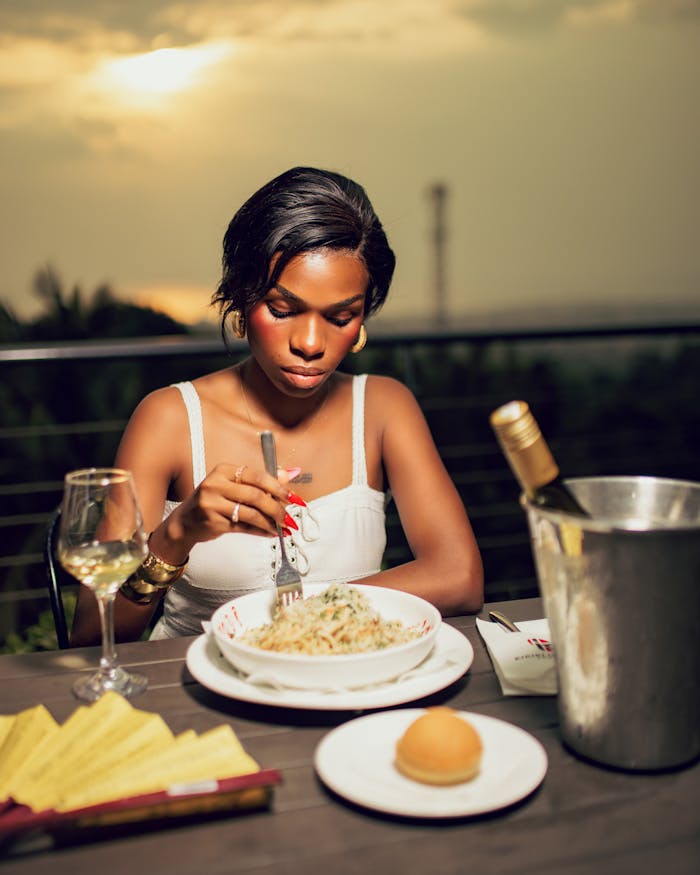 gallery-1 Woman enjoying pasta and wine outdoors at sunset.