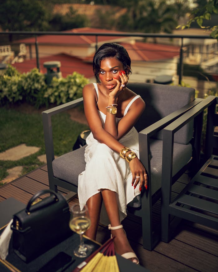 services-03 Elegant woman in white dress enjoying outdoor seating with a drink, exuding sophistication.